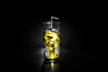 Cocktail glass splashing on dark toned smoky background or colorful cocktail in glass. Party club entertainment. Mixed light.