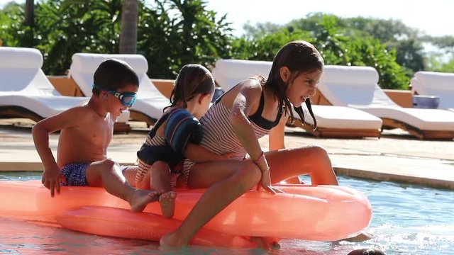 Children at the pool playing with inflatable mattress