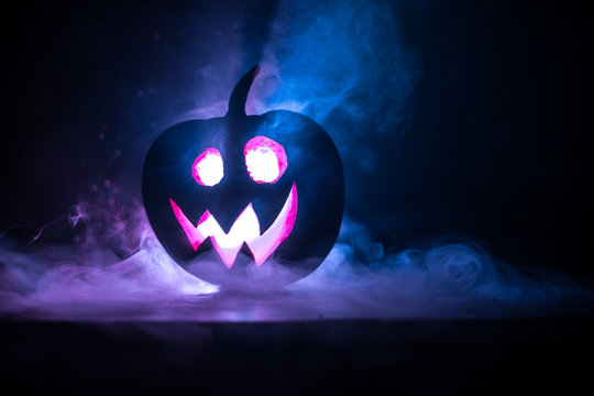 Halloween pumpkin smile and scrary eyes for party night. Close up view of scary Halloween pumpkin with eyes glowing inside at black background.