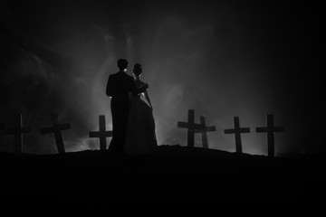 Halloween. Scary zombie bride on a night cemetery holds a pumpkin lantern.