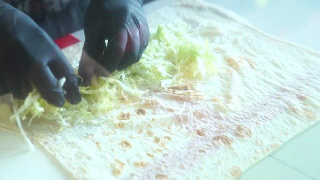 Chief hands wrapping traditional shawarma roll with meat and vegetables
