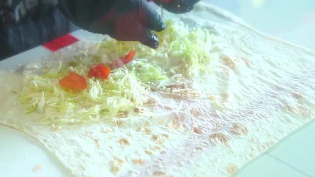 Chief hands wrapping traditional shawarma roll with meat and vegetables