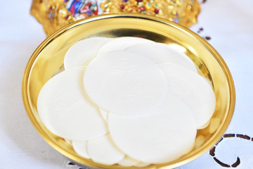 Golden paten with white hosties.