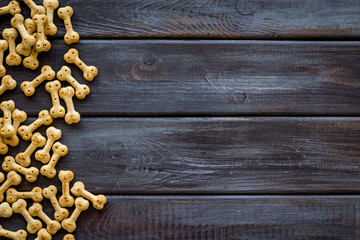 Dry pet food in shape of bone on wooden background top view copyspace