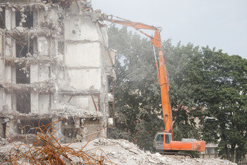 Demolition of building with excavator-destroyer for high-altitude work. Grab crane with hydraulic...