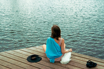 Woman sitting with a dog on dock at the lake.