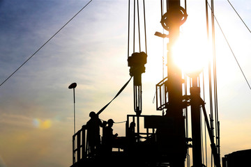 The pumping unit is operating in the oil field in the evening, silhouetted against the sky