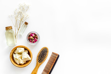 Bottle with jojoba, argan or coconut oil, comb for hair style on white background top view mock up