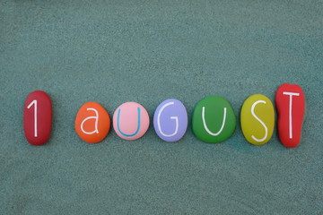 1 August, calendar date composed with multi colored stones over green sand
