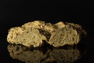 Group of one whole two slices of fresh cereal baguette isolated on black glass