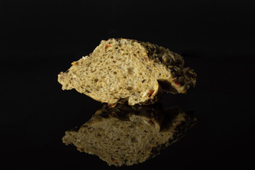 One slice of fresh cereal baguette isolated on black glass