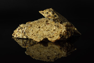 Group of three slices of fresh cereal baguette isolated on black glass