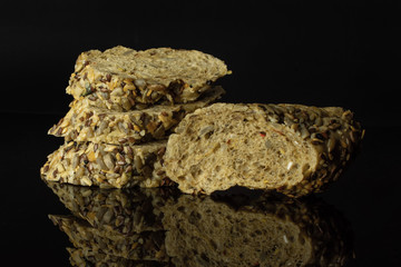 Group of one half two slices of fresh cereal baguette isolated on black glass