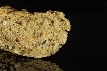 Closeup of one half of fresh cereal baguette isolated on black glass