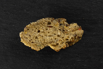 One slice of fresh cereal baguette flatlay on grey dark stone