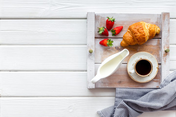 croissant, fruit and coffee with cream for breakfast on the tray on white wooden background top view space for text