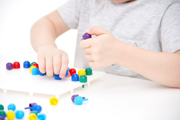 Obraz na płótnie Canvas little boy plays with a plastic mosaic. Educational games. Montessori Preschool early develop