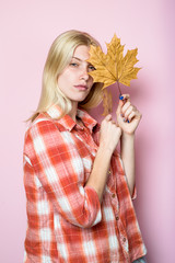 Fototapeta premium Autumn woman. Serious girl in casual wear holds yellow leaves. Fashion trends for fall. Autumn woman with golden maple leaves. Autumn fashion. Blond girl with golden leaf. Autumnal mood. Autumn sales.