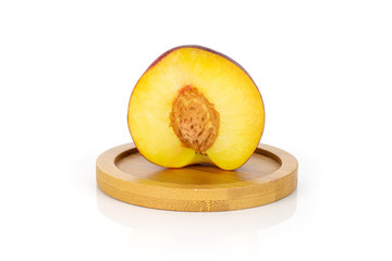 One half of fresh red nectarine on a round bamboo coaster isolated on white background