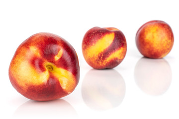 Group of three whole fresh red nectarine placed diagonally in a line isolated on white background