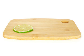 One slice of fresh green lime on a bamboo cutting board isolated on white background