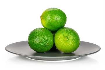 Group of four whole fresh green lime on a ceramic grey plate isolated on white background