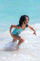 Fototapeta na wymiar Young happy girl runs out of the water in beautiful tropical beach