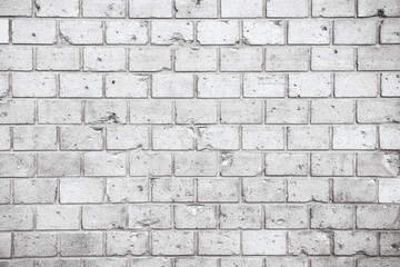 Simple grungy grey white brick wall with light and dark gray shades seamless pattern surface texture background. Wall weathered under the elements and marked with holes, cracks and imperfections.