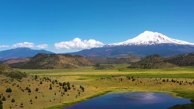 The snow-capped Peaks of Mt Shasta in the Cascade range of mountains Siskiyou County California. Reflecting on the surface of a lake in the foreground