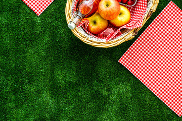 picnic in summer with products, apples, drinks on green grass texture background top view space for...