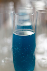 Blue drink in a clear glass cup among empty cups