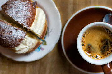 Cup of coffee and cream doughnut on a wooden table