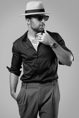 Beautiful brutal tanned hipster man in a black shirt, hat and glasses