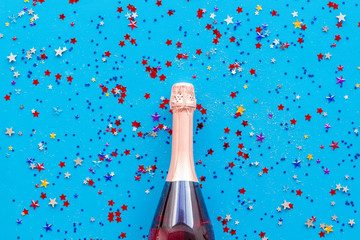 Party with champagne bottle and colorful party streamers on blue background top view pattern
