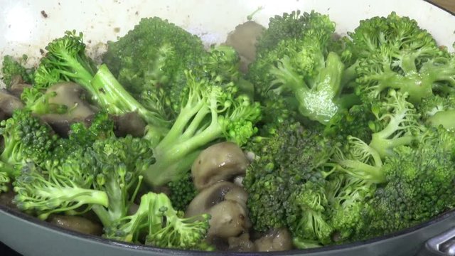 Fresh broccoli and mushrooms simmering in a pan
