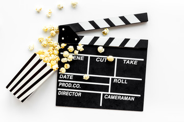 Movie premiere concept with clapperboard, popcorn on white background top view