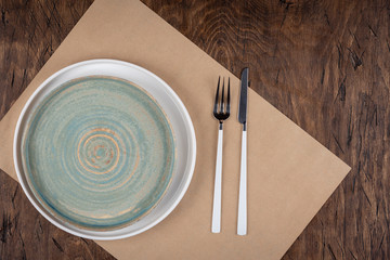 Empty plate with fork and knife on colored wooden background, top view, copy space, mock-up