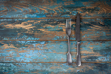 Empty plate with fork and knife on colored wooden background, top view, copy space, mock-up
