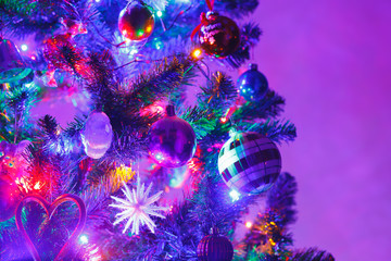 Obraz na płótnie Canvas Christmas tree with decorations and purple illumination, close-up view