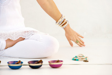 Woman sitting in meditation with sound healing bowls and mala beads. 