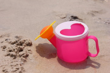 Fototapeta na wymiar Toy watering can on the sand of the sea coast.
