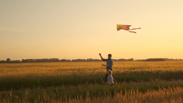Father and son playing with a kite in nature at sunset. Unity of family and outdoor recreation. Happy family. Slow motion
