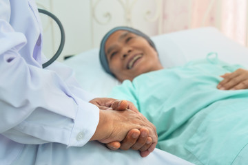 selective focused of doctor's hands hold patient's hands to give encouragement to patient during chemotherapy to cure cancer