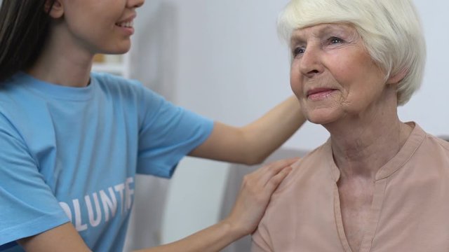Lady volunteer combing aged woman, social worker visiting retired person at home