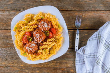 Rotini pasta with meatballs in tomato sauce and olives in bowl.