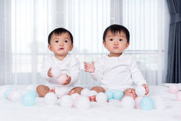 cheerful twin babies playing color ball on  bed