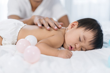 Obraz na płótnie Canvas baby sleeping on bed with hand patting