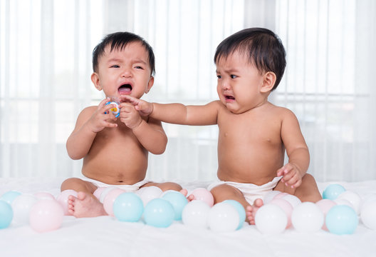 Two Twin Babies Crying On Bed