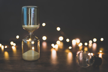 time for new ideas hourglass and lightbulb surrounded by fairy lights bokeh