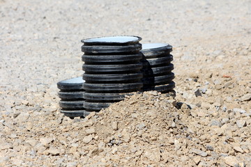 Three plastic pipes sticking out of ground surrounded with gravel at local construction site on...